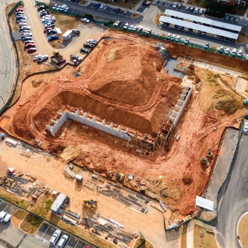 Aerial view of red-soil construction site with equipment and structures.
