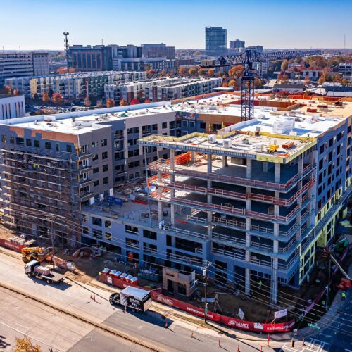 Aerial view of tall building under construction amid urban roads.