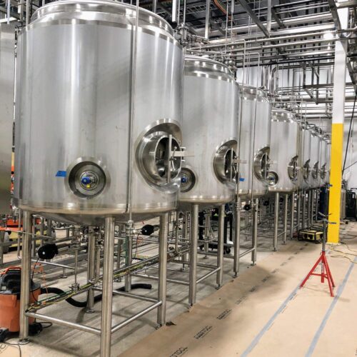 Large stainless steel tanks with ports and pipes in a facility.
