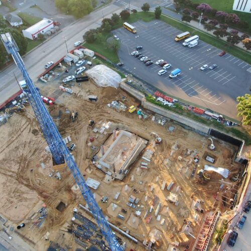 Aerial view of construction site with crane and parking lot.
