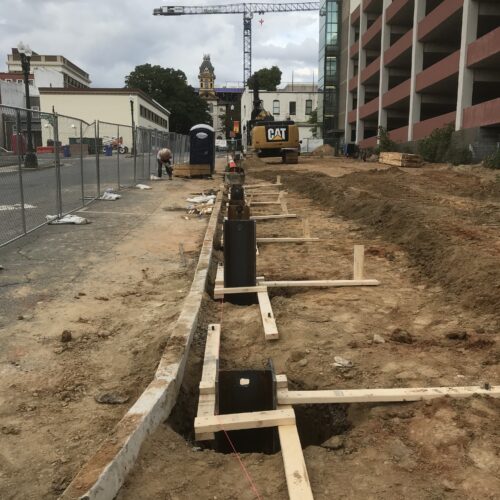 Construction site with wooden frames, workers, crane, excavator, garage.