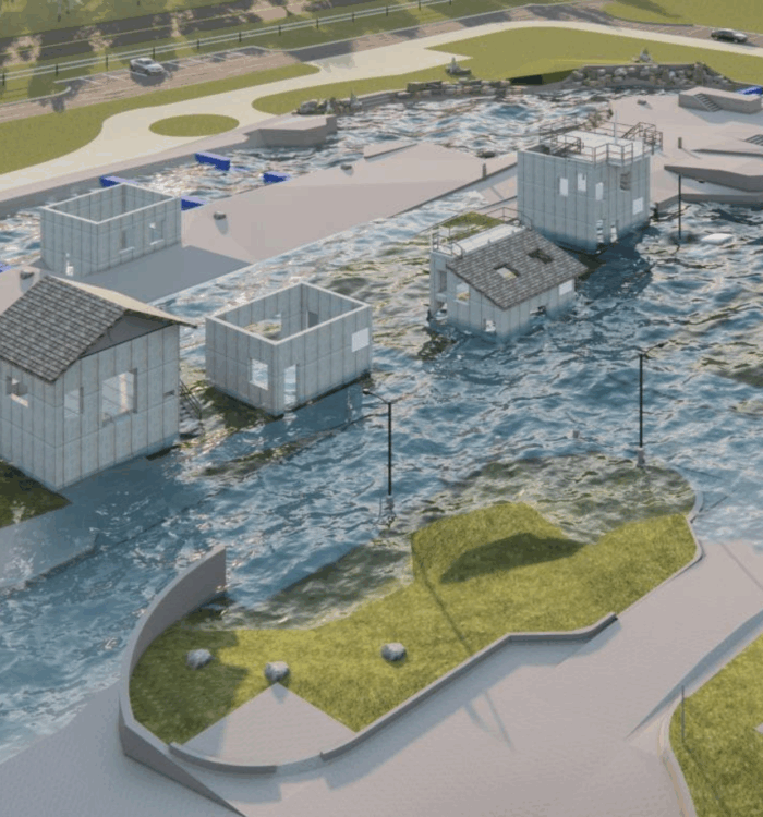 Aerial view of a water channel, small model houses, grass, and roads.