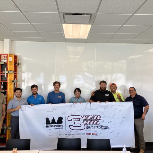 Eight people indoors holding “3 Million Hours No Lost Time” banner.