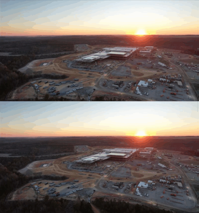 Mirrored aerial view of construction site, sunset, buildings, cars, woods.