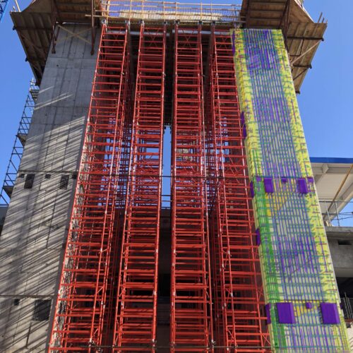 Concrete building under construction with scaffolding and digital grid.