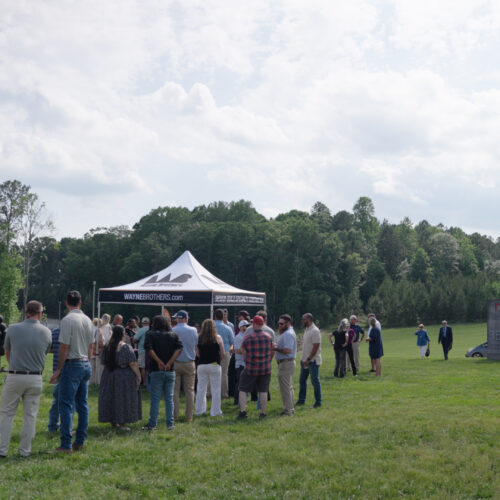 People line up outside a branded tent at an outdoor event.