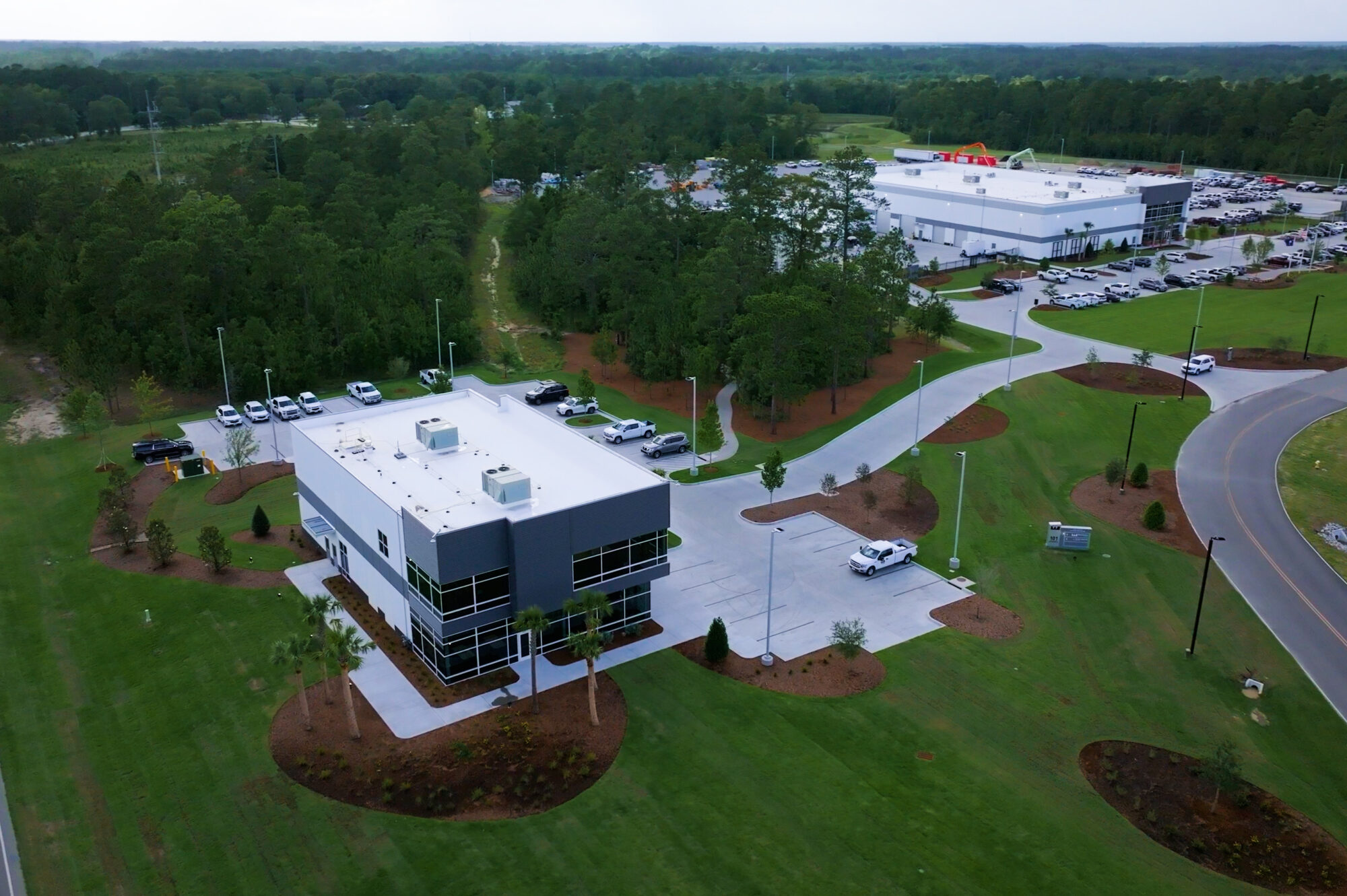 Aerial view of two office buildings amid greenery and roads.