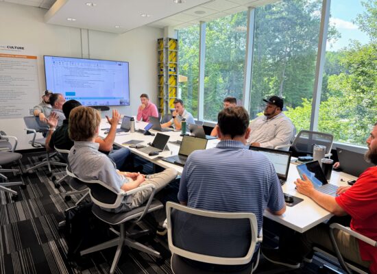 Group of people sitting in a boardroom with laptops