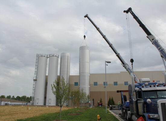 Two crane arms extended, one lifting a silo tower