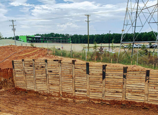 Construction site: wood walls, exposed soil, power lines, green building.