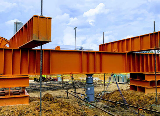 Large orange steel beams assembled on a construction site.