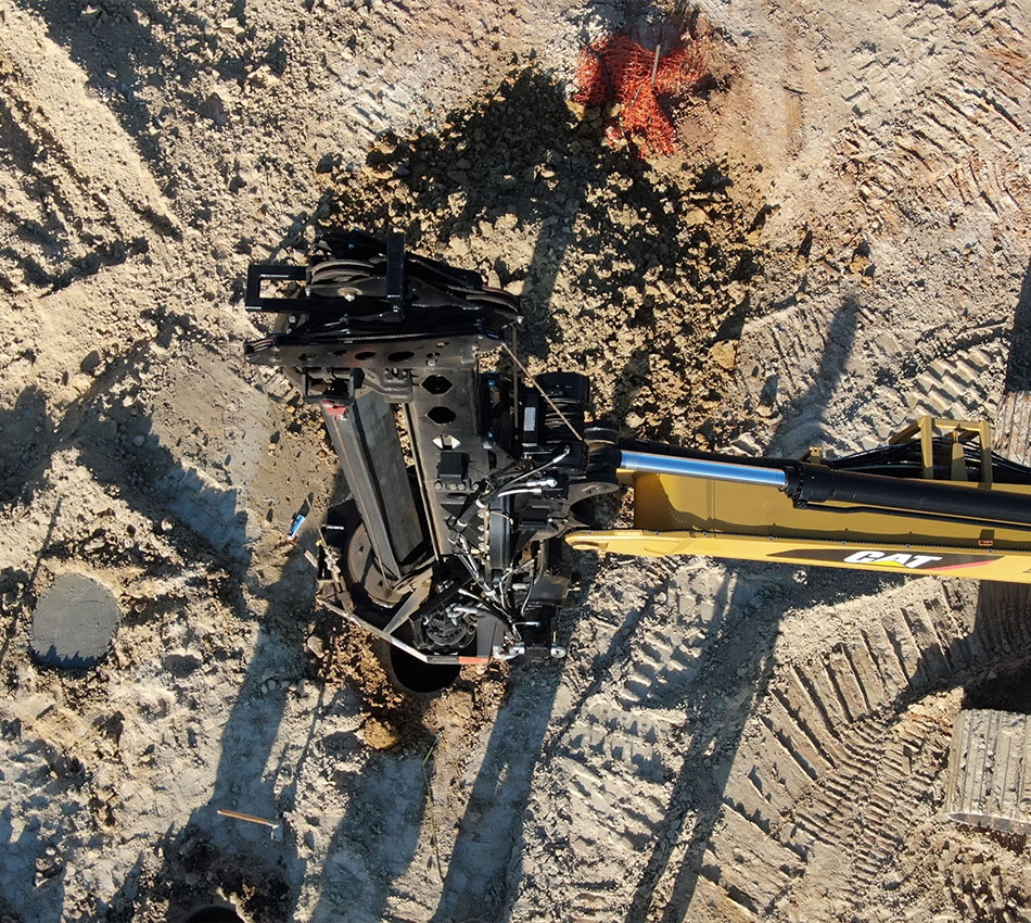 Aerial view: Caterpillar excavator drills sandy soil at construction site.