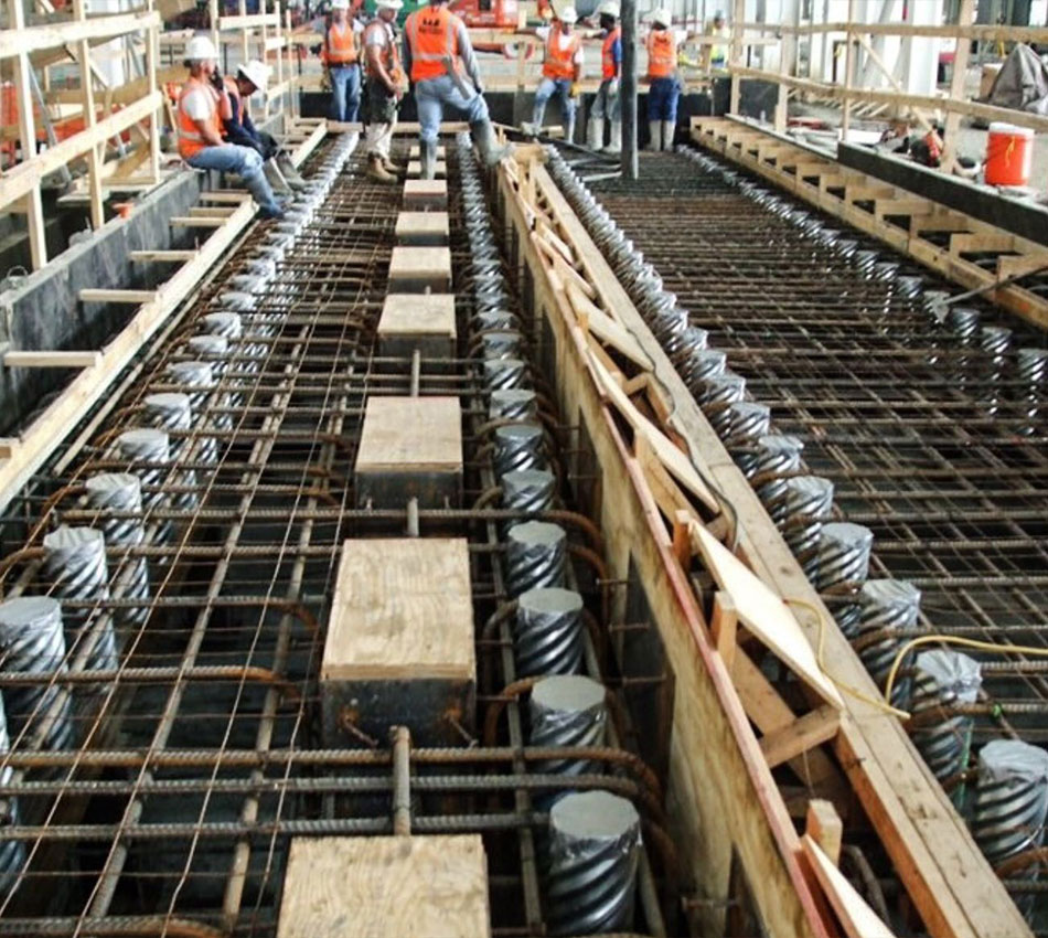 Workers in vests stand by concrete with rebar and forms.