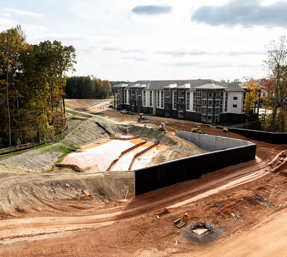 Partially built apartments, machinery, dirt roads, mud pools, trees.