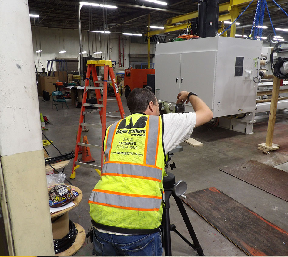 Worker in safety vest looked through scope on tripod.