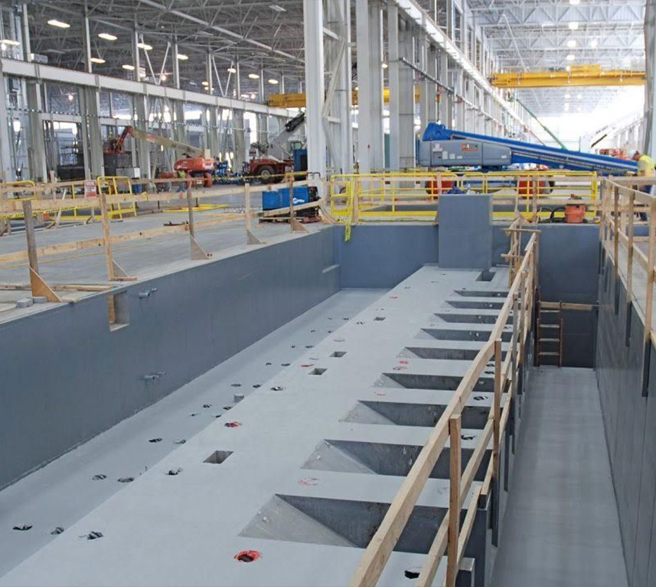 Industrial facility: unfinished dry dock, railings, equipment present.