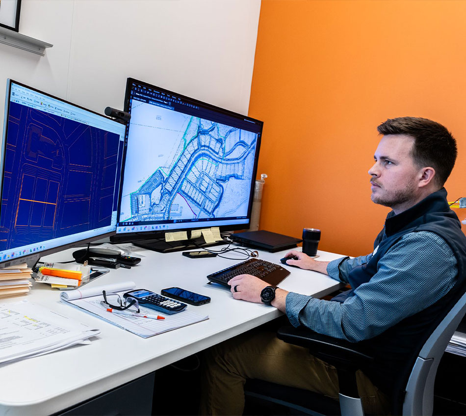 Man works at desk viewing 3D drawings on computer screen