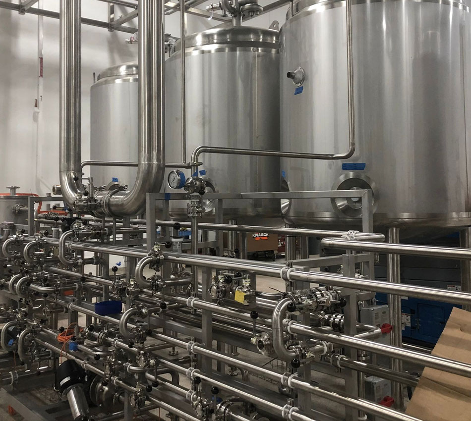 Industrial stainless steel tanks, pipes, valves, gauges interconnected.
