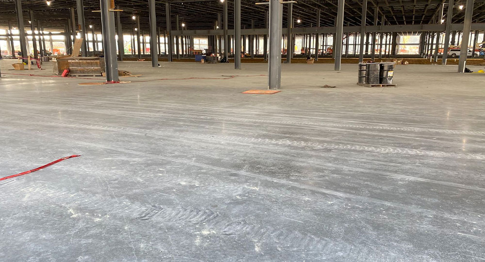 Warehouse under construction: new concrete floor, steel beams, materials.
