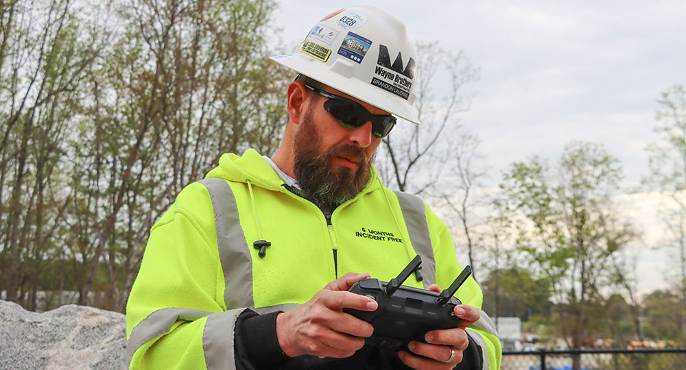 Construction worker in neon jacket uses remote outdoors