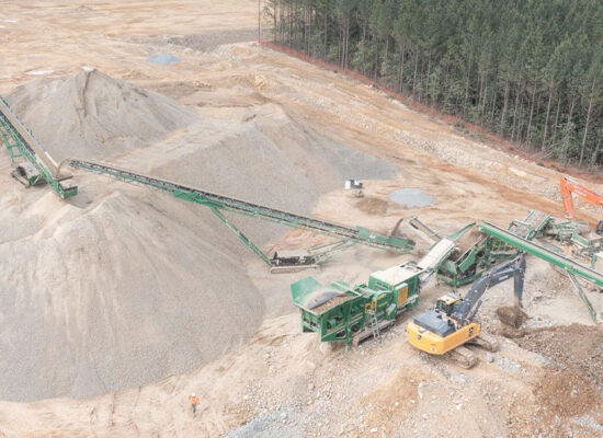 Aerial view: gravel site, conveyor belts, machinery, and forest.