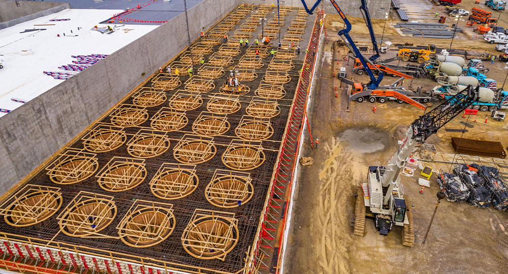 Aerial view: Workers assemble wooden forms on construction site.