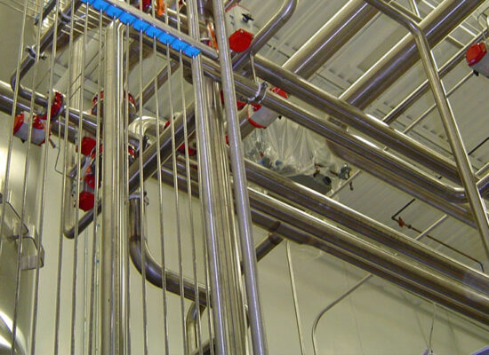 Clean stainless steel pipes, valves, in a bright facility.