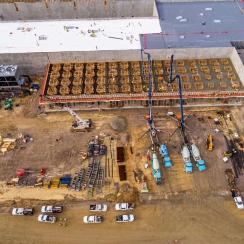Aerial view of construction site with vehicles, workers, and materials.