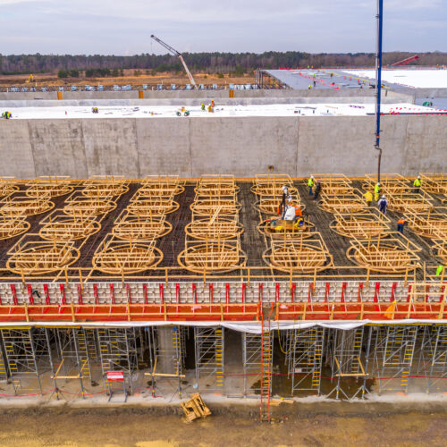 Workers build wooden framework and scaffolding on a concrete structure.