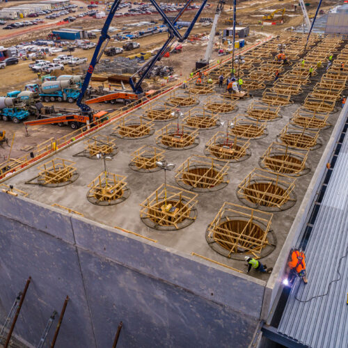 Aerial view of workers assembling circular molds on concrete.