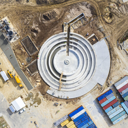 Aerial view of circular structure under construction at industrial site.