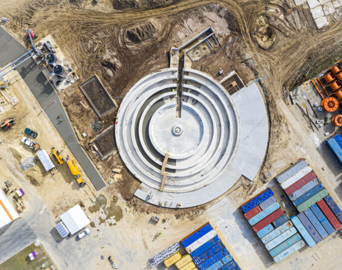 Aerial view of circular structure under construction at industrial site.