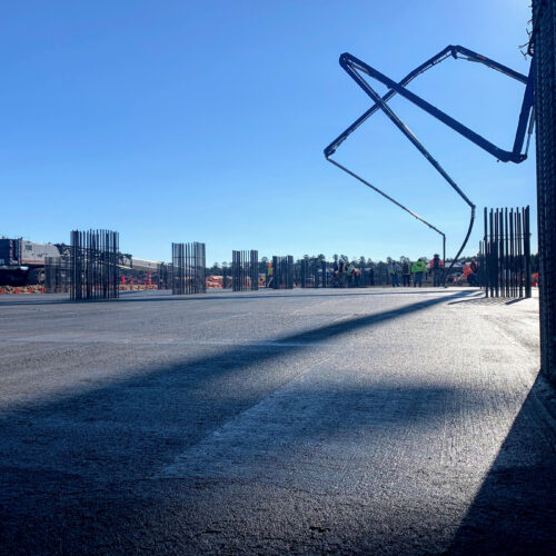 Concrete slab, exposed rebar, and pump truck at construction site.