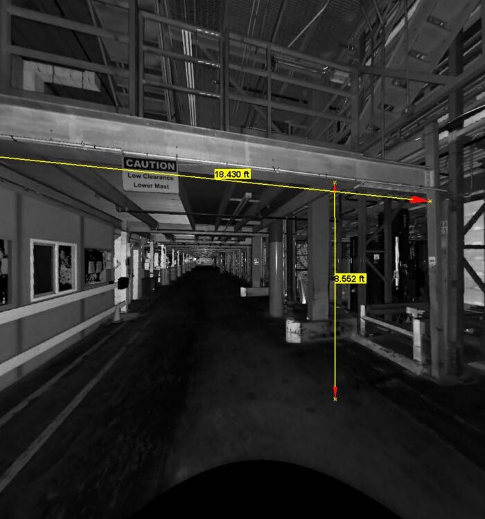 Black and white corridor, low clearance marked by yellow arrows.