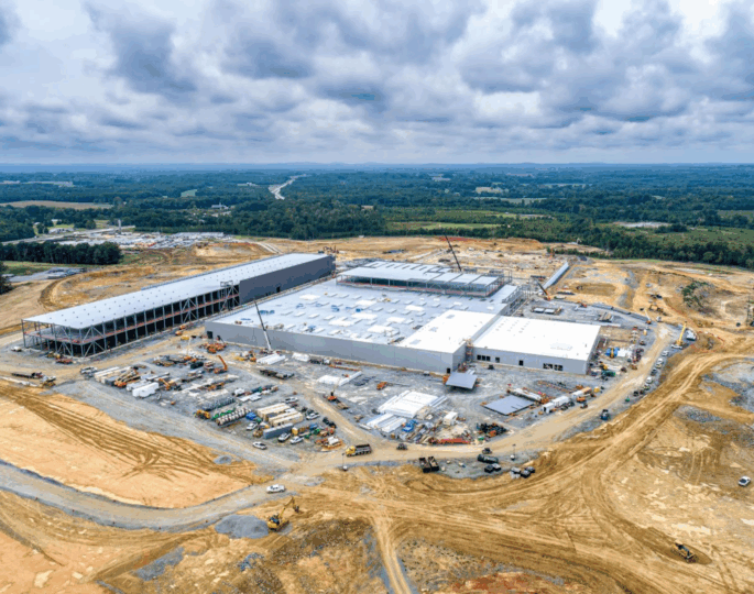 Aerial view of industrial building construction site by forest.