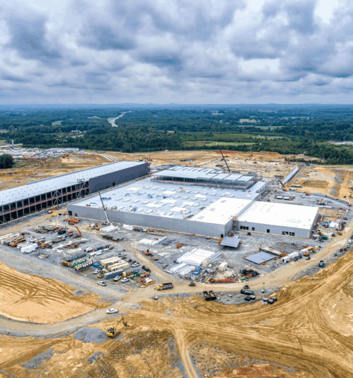 Aerial view of industrial building construction site by forest.