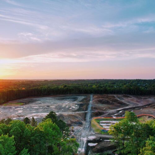 Aerial view of sunset construction site with dirt and trees.
