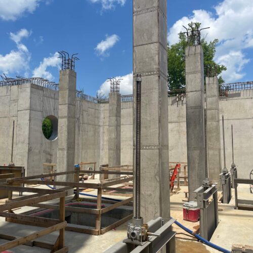 Concrete columns with rebar under construction beneath a blue sky.
