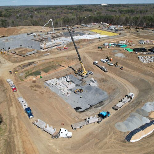 Aerial view of a busy construction site with cranes and trucks.